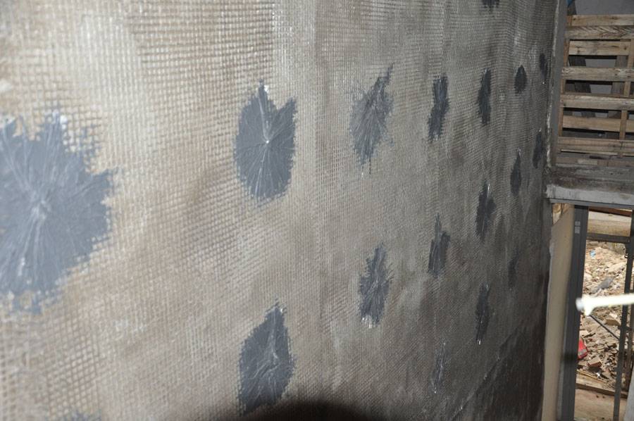 Immagine di una rete in materiale composito collegata alla parete in muratura mediante fiocchi per intonaco armato.