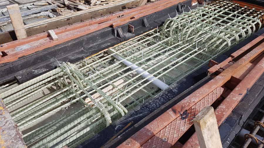 Cassero tramviario con rete e staffe curve in barre GFRP di vetroresina e condotto passacavi centrale, fase pre-getto in stabilimento.