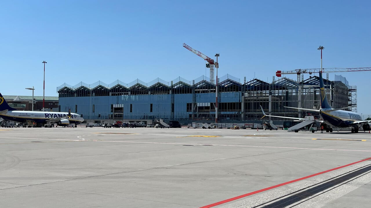 Ampliamento terminal aeroporto Venezia Marco Polo con nuova struttura in acciaio e vetro, cantiere in fase di costruzione.