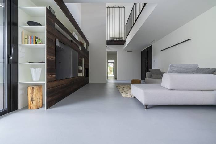 Soggiorno moderno con pavimento in rivestimento continuo grigio Nativus di Nord Resine, superficie senza fughe, arredi contemporanei e finiture di design.