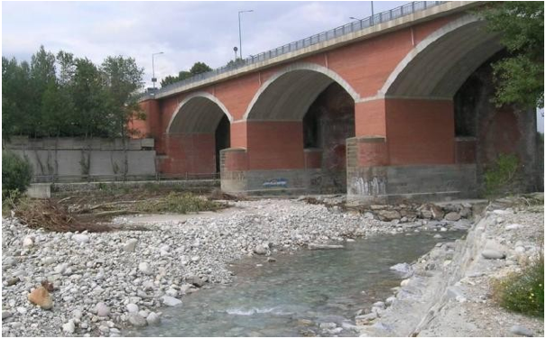 Vista attuale del ponte in muratura sul fiume Gesso, con archi in laterizio e alveo fluviale a secco parziale.