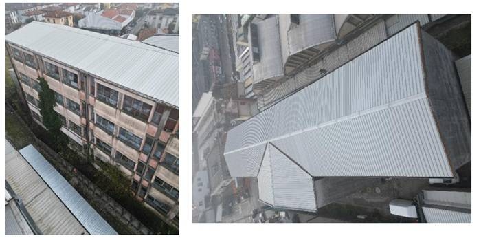 “Veduta dall’alto del tetto dell’edificio scolastico esistente, copertura metallica a falde inclinate di colore grigio, che evidenzia lo stato attuale della struttura prima dell’intervento di ristrutturazione.”