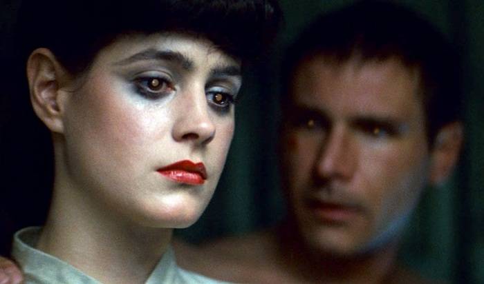 Blude Runner” del regista Ridley Scott, tratto da “Il cacciatore di androidi” di Philip K. Dick e uscito nelle sale nel 1982. Il fotogramma inquadra la replicante Rachel (interpretata da Sean Young) e lo sfuocato cacciatore di taglie Rick Deckard (interpretato da Harrison Ford).