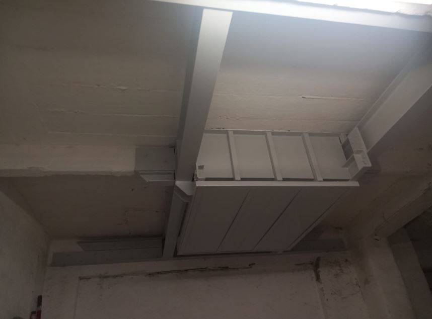 Incastellatura metallica per ascensore installata sotto solaio in edificio esistente, con travi di irrigidimento e staffe di ancoraggio per vano scala ridotto.