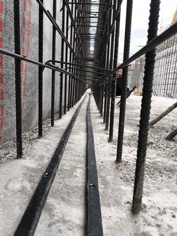 Dettaglio ravvicinato dell’armatura in acciaio di una parete in calcestruzzo. Al centro si notano due cordoli sigillanti neri posizionati alla base, che indicano l’applicazione della sigillatura con sistema WT Construction.