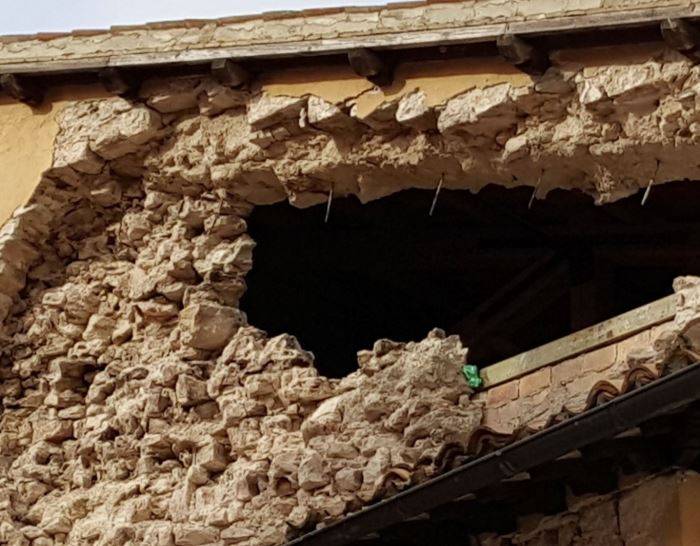 Crollo di una parete muraria sommitale durante il sisma Centro Italia 2016: distacco della muratura e cedimento dei punti di connessione del cordolo in c.a.