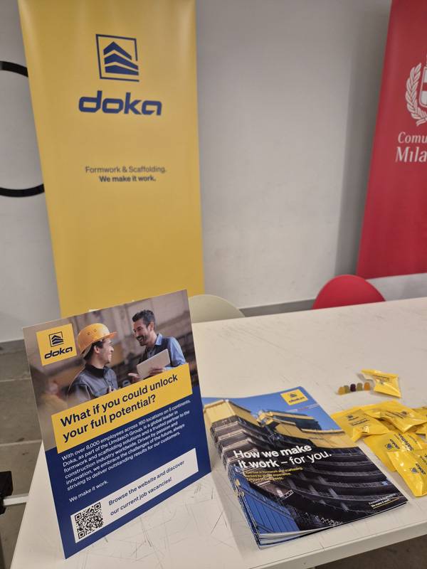 Stand Doka Italia al Career Day Politecnico di Milano con materiali informativi su opportunità di lavoro e carriera nel settore costruzioni, casseforme e progettazione edilizia