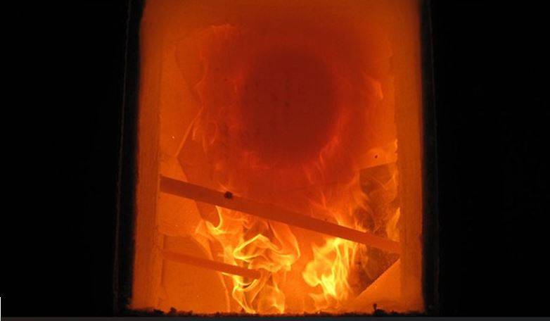 Fase iniziale di un test di resistenza al fuoco, dove un elemento in legno è sottoposto all'azione diretta delle fiamme in un ambiente controllato.