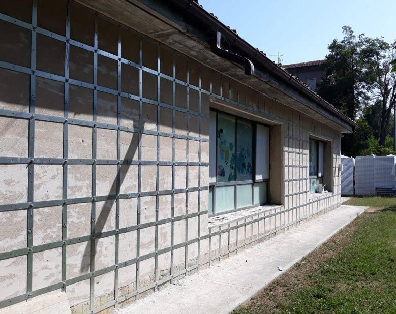 Vista laterale della scuola con applicazione completa del sistema Sismagrid sulle murature esterne.